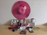 Photo showing pink sun hat, slippers, makeup items, necklace, and mug with box.