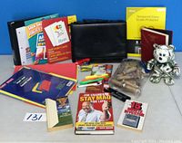 Full lot overview showing black portfolio case, finance books including investment titles, stationary items like highlighters and markers, file folders, and screen protector box.