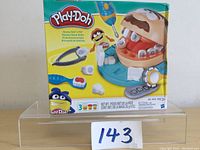 Front view of the Play-Doh Doc Drill N Fill box showing the playset, tools, and three cans of Play-Doh, new in packaging.