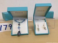 Both necklace and earrings displayed in their original blue Wedding Day branded boxes on table.