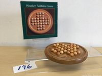 Photo of complete wooden solitaire game board and the green box with image of the board shown behind it.