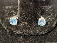 Front view of blue stone 10KT gold stud earrings on black background.