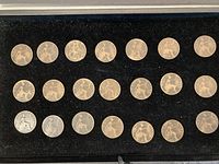 Photo showing 21 large worn pennies arranged in rows on black felt.