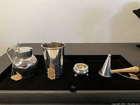 Overview of four silver items on black tray