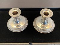 Pair of vintage Birks sterling silver candle holders displayed side by side on a black background, showing polished surfaces and classic design.