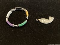 Photo showing multicolored jade segment bracelet with silver spacers on black background