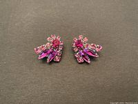 Pair of vintage Sherman earrings showing front view of pink rhinestone clusters in various shapes on black background.