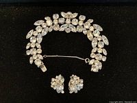 Full overview of clear rhinestone bracelet and cluster earrings on black background