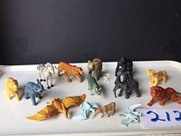 Full view of all 14 rubber animal figurines arranged on a white tray against a black background