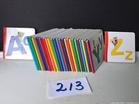 Display of all 26 alphabet board books arranged standing side by side showing colorful spines with distinct colors for each book and visible front covers for letters A and Z.