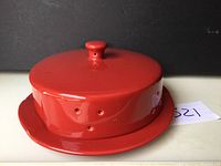 Red ceramic appetizer baker with lid fully closed, showing vent holes and knob