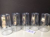 Five clear plastic Bahama drinking glasses placed upside down on a dark surface, showing tapered design with vertical ridges.