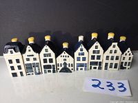 Front view of all eight KLM Amsterdam ceramic houses in a row showing their different architectural styles, blue and white color with yellow chimney tops