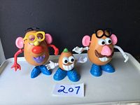 Front view of all three Mr. Potato Family figures placed side by side on a white surface with number 207 card.