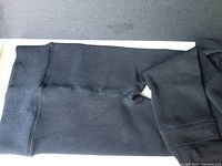 Close-up image showing one pair of black warm tights with elastic waistband and reinforced seam detail.
