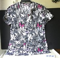 Full view of the nurses top hanging on a rack, showing butterfly pattern and shape