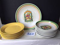 Overall view of large salad bowl, 6 smaller decorative bowls, and 6 yellow plates arranged flat