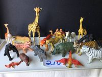 Full view of all 15 rubber animal figures arranged on a white surface, including giraffes, lions, tigers and others.