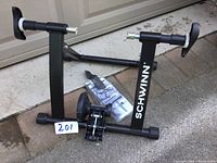 Full view of Schwinn branded black metal foldable bike trainer frame on concrete floor showing the main frame and resistance mounting points.
