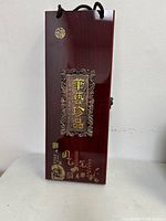 Exterior view of the rectangular polished wooden box with Chinese script and decoration on top, showing the lot packaging.