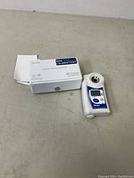 Two Atago handheld refractometers with original packaging, placed on flat surface.