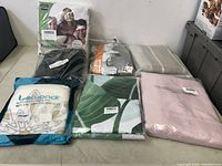 Overview of the lot showing six packaged home textile items including bamboo towel, mattress protector, blackout curtains, pillow covers, shower curtain