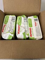 Three packs of Huggies Natural Care Sensitive wipes inside a cardboard box, sealed packaging.
