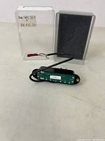 Seymour Duncan Hot Rails humbucker pickup alongside its original plastic case with foam insert, showing the pickup's circuit board and wiring.