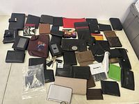 Overview of all wallets laid out on a table showing various colors, styles, and conditions, with some new sealed and others worn.