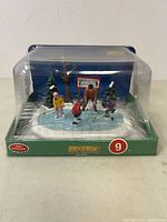Front view of Lemax mini hockey table decor in plastic packaging showing players and scenery.