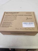 Closed original box of Motopower automatic battery charger/maintainer labeled Junior and Eco Friendly.