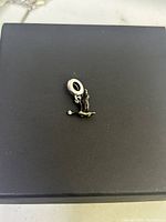 Close-up of Pandora Canadian Goose & Maple Leaf dangle charm lying on a black surface, showing detailed front and side views.