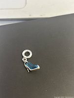 Top view of Pandora charm showing blue glass slipper and Pandora stamp on loop.