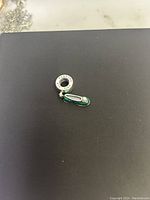 Photo of the Pandora Disney Tinkerbell charm on a black surface showing the charm and engraved ring.