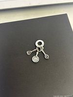 Three close-up photos of the new Pandora cooking chef charm set - spatula, frying pan, and whisk charms on a black background.