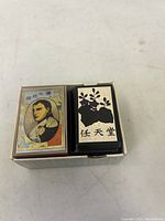 Top view showing open box with one deck's back card showing Japanese floral and character designs.