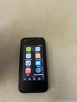 Oioni Mini Smartphone front view showing home screen with various app icons and front camera.