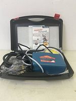 Pressure steam cleaner unit with hose, attachments, and user guide inside black carrying case