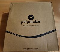 Closed cardboard box with Polymaker branding for 3D printing filament.