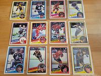Fronts of 12 hockey cards laid out on a wooden surface showing player images and team logos.
