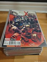 Stack of comics topped by Uncanny X-Men #600 variant cover with multiple characters including Wolverine, Psylocke, and others in battle stances.