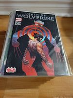 Top comic is Death of Wolverine, bagged and boarded, visible front cover with target graphic and character depiction.