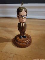 Front view of Dwight Schrute figurine on wooden base