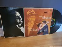 Two Frank Sinatra vinyl records, one "Songs for Swingin' Lovers!" with colorful cover, the other "Collectibles of the Early Years" with black and white cover and vinyl records visible
