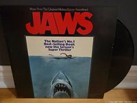 Front cover of Jaws soundtrack vinyl record showing iconic poster art of swimmer and shark.