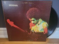 Front cover of Jimi Hendrix Band of Gypsys album showing Jimi Hendrix playing guitar in colorful lighting.
