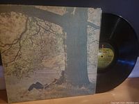 Vinyl LP partially exposed from cover, showing large tree artwork and black vinyl disc label with Apple Records design