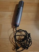 Full length view of the small Sony microphone with attached cable and 3.5mm aux plug on a wooden surface.