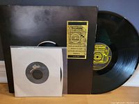 Black vinyl record and cover of 'This Is Radio Clash' EP with distinctive yellow and black label and artwork, alongside a smaller 7" single record in a white Epic sleeve.