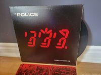 Front view of The Police 'Ghost in the Machine' LP vinyl record picture sleeve showing red digital-style artwork and text.
